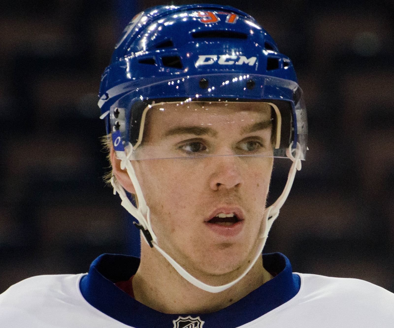 Close portrait of Connor McDavid through his helmet cage, July 2015.