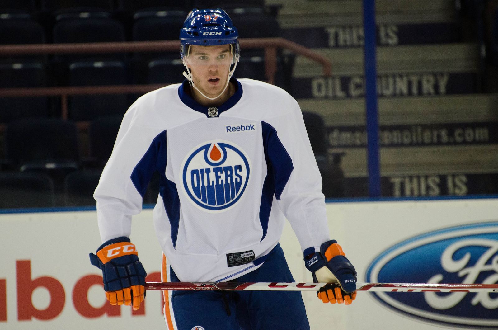 Connor McDavid at the boards during Oilers development camp, "This Is Oil Country" signage behind him, July 2015.